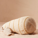 bottom view of woven ivory bag with  yellow/brown stripes on a beige background