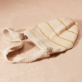 Flat view of Ivory woven bag with yellow/brown stripes on a sand background