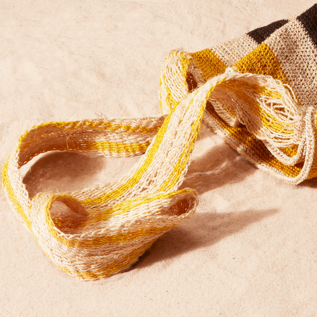 Close up view of ivory and yellow strap against a sand background