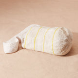 Bottom view of ivory woven bag with thin yellow stripes and an ivory woven strap on a sand background