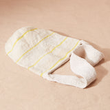 Ivory woven bag flat view with thin yellow stripes and a solid woven strap on a sand background