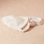 Flat view of woven ivory bag on a sand surface