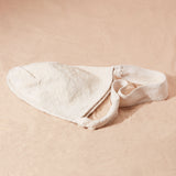 Flat view of woven ivory bag on a sand surface