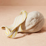 Bottom view of ivory and yellow woven striped bag with V patterned yellow and ivory strap on a beige background