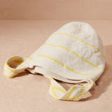 Flat view of ivory and yellow striped woven bag on a sand background