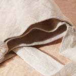 Detail view of ivory woven bag showing two interior compartments of the bag on a sand surface