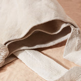 Detail view of ivory woven bag showing two interior compartments of the bag on a sand surface