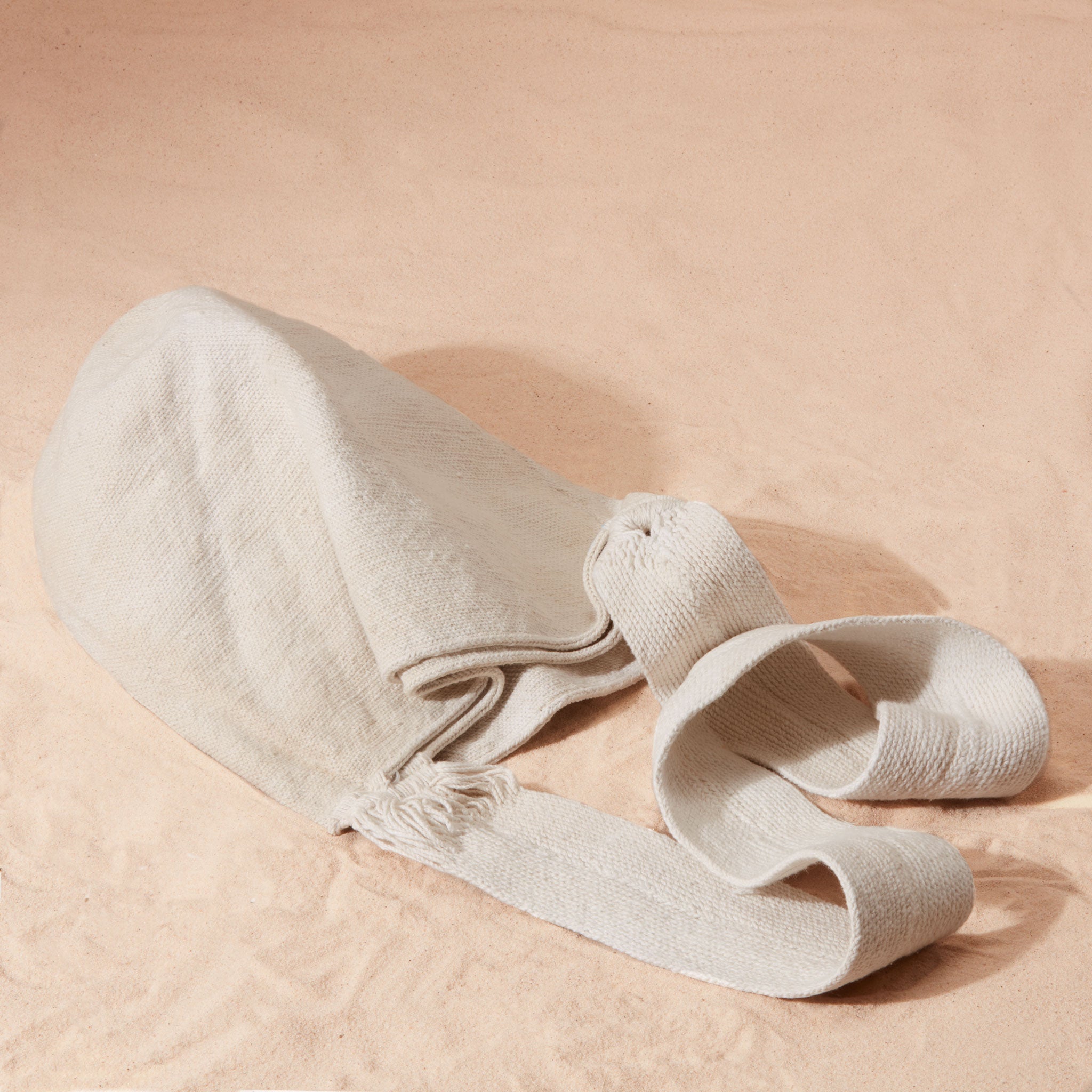 Flat View of ivory woven bag on a sand background