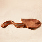 Flat View of Brown-orange and grey woven bag with strap on a sand background