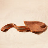 Flat View of Brown-orange and grey woven bag with strap on a sand background