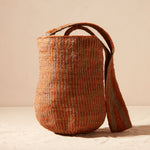 Woven brown-orange and grey bag with a strap on a beige background
