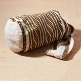 Side view of ivory, black and yellow woven bag on a sand background