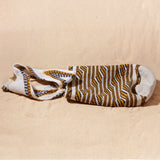 Flat view of ivory, black and yellow woven bag on a sand surface