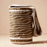 Ivory, black and yellow woven bag against a beige background