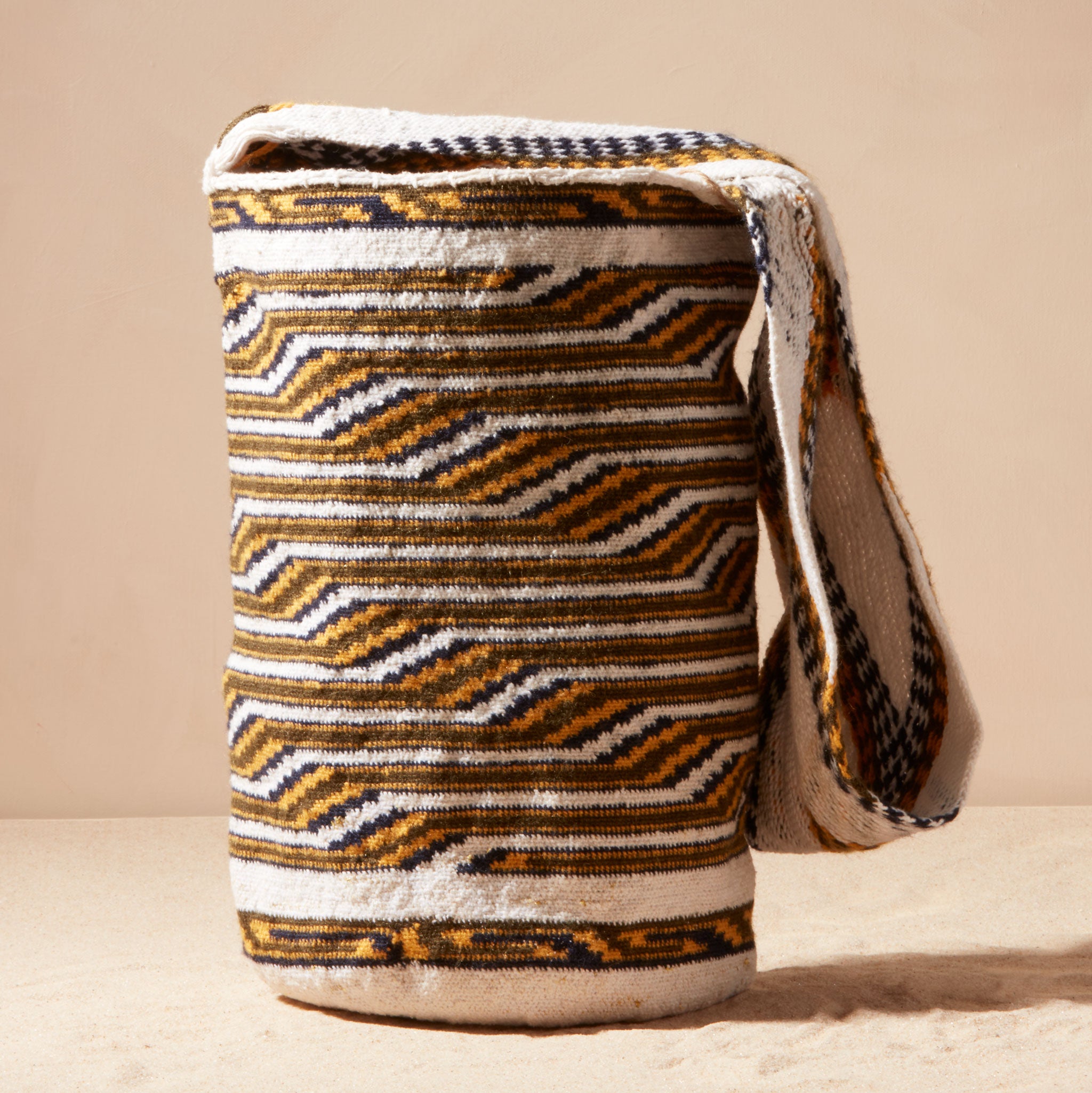 Ivory, black and yellow woven bag against a beige background