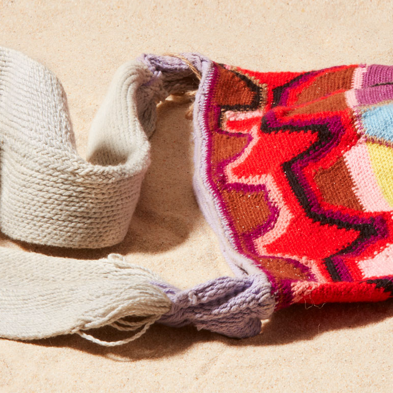Detail view of colorful patterned woven bag on a sand background