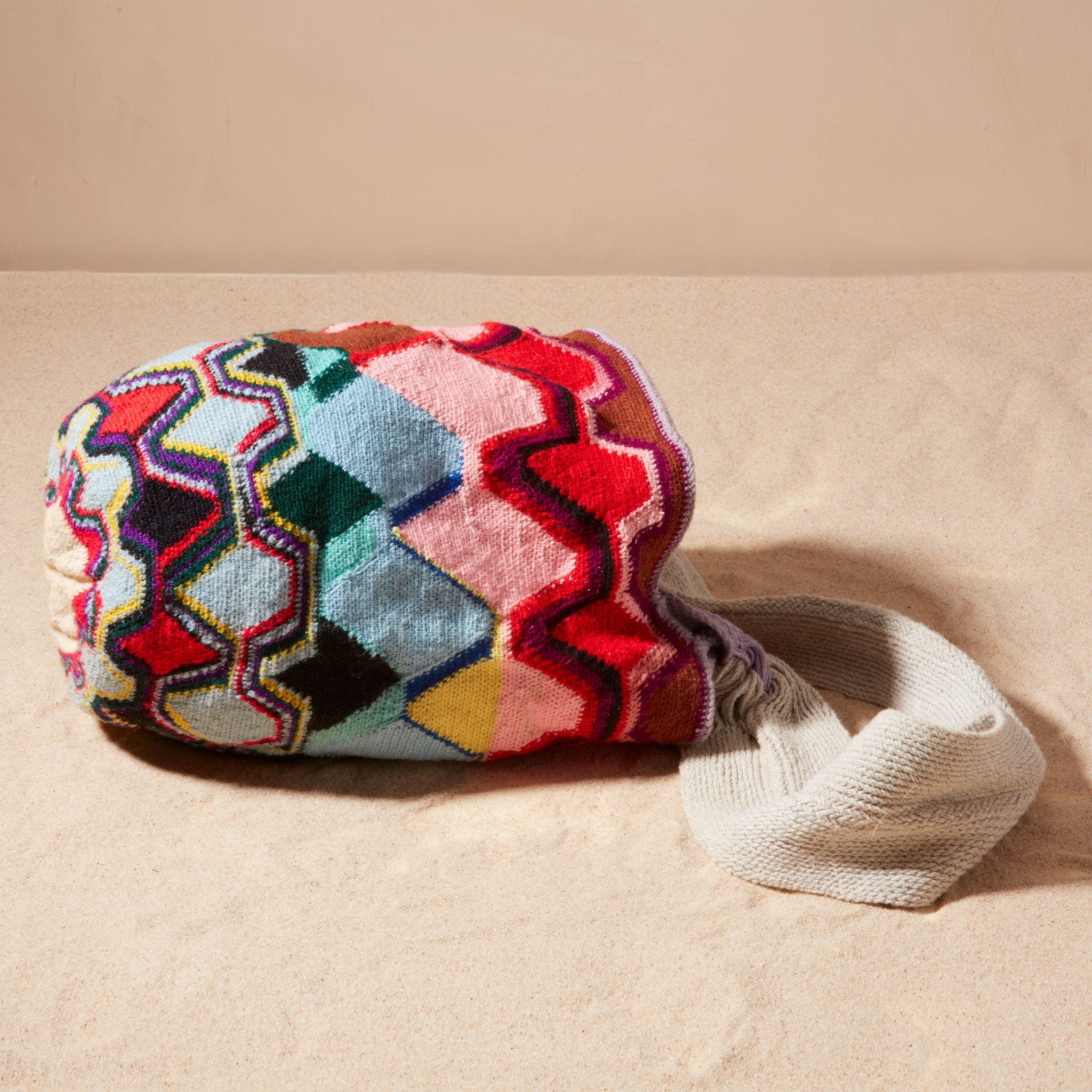 Side view of colorful patterned woven bag on a beige background