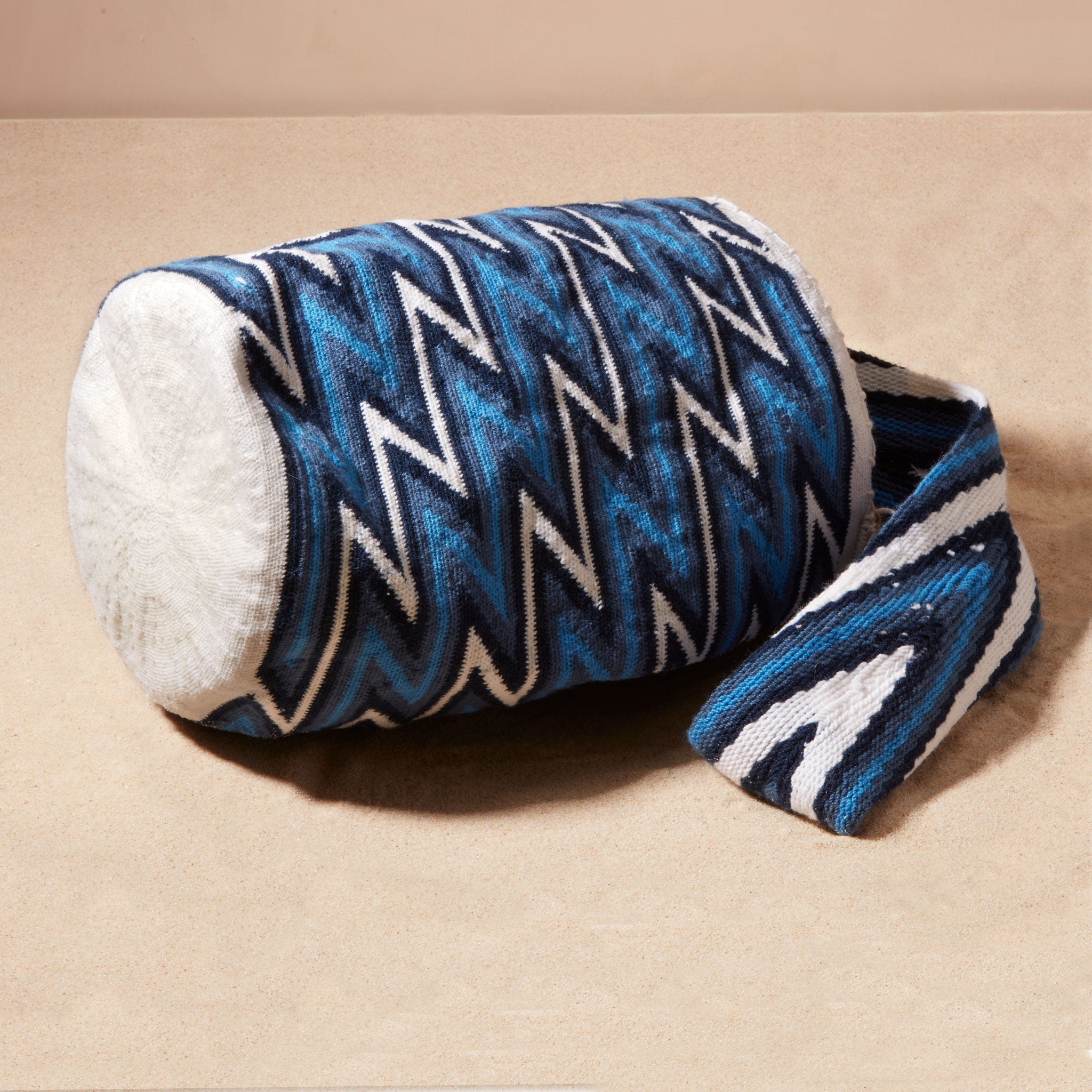 Bottom view of woven bag with blue and white zigzag pattern against a beige background