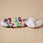 Flat view of colorful patterned woven bag on a sand background