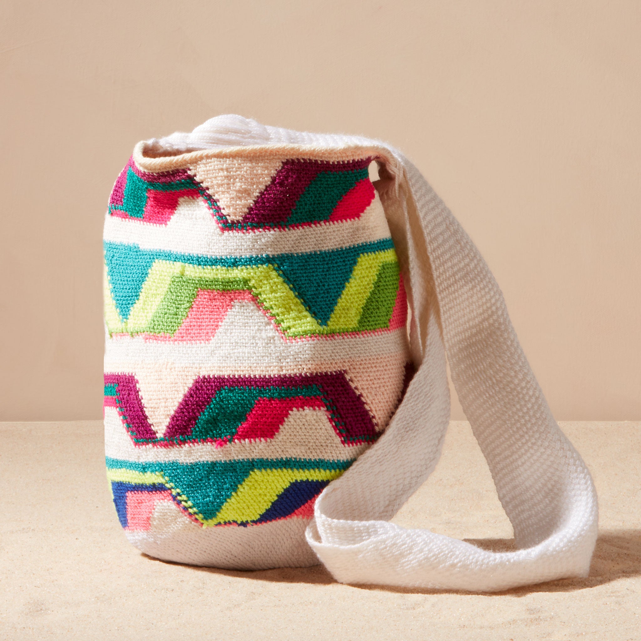 Colorful woven bag with geometric pattern on a beige background