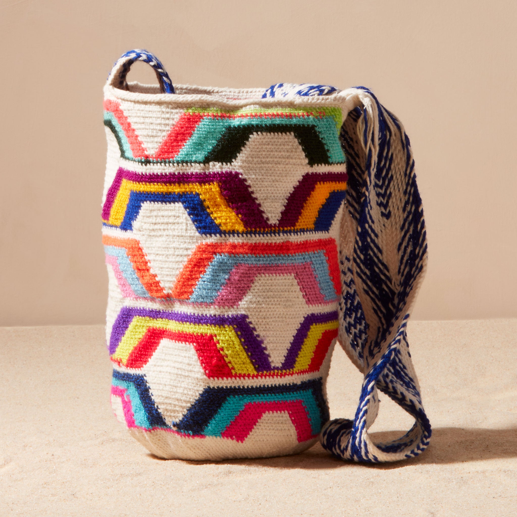 Colorful woven bag with geometric pattern on a beige background