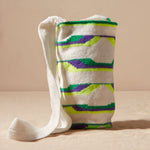 Ivory, green, neon green, purple woven bag against a beige background