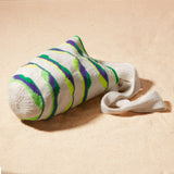 Side view of ivory, green, neon green, purple woven bag on a sand background