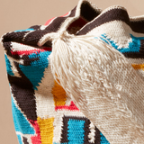 Close-up of a colorful woven bag  ivory strap on a beige background