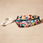 Flat view of colorful patterned bag with a strap on a sand background