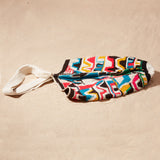 Flat view of colorful patterned bag with a strap on a sand background