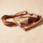 Flat view of textured woven bag with a zigzag pattern on a sand background