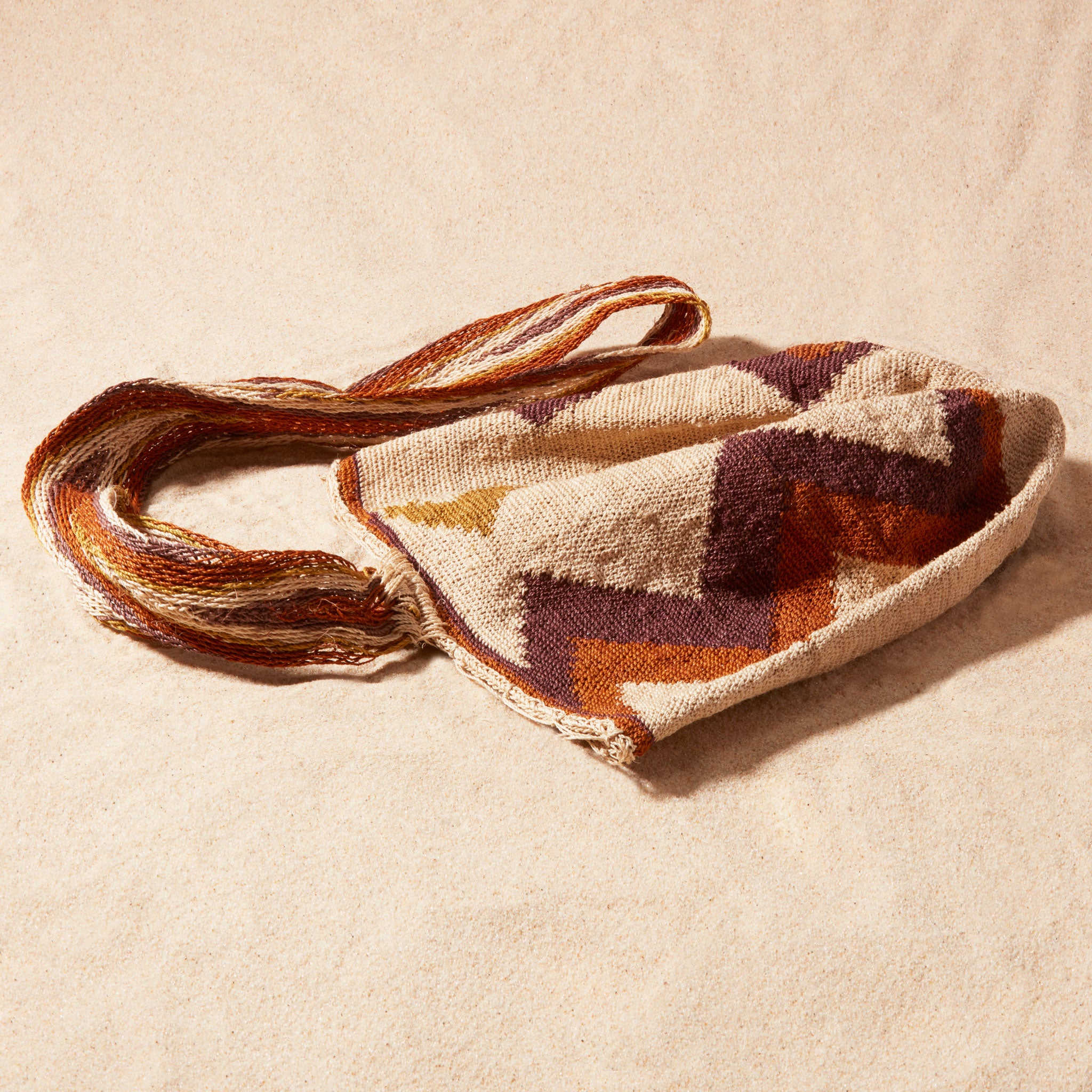 Flat view of textured woven bag with a zigzag pattern on a sand background
