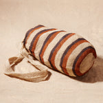 Side view of striped woven bag on a sand background