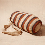 Side view of striped woven bag on a sand background