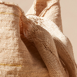 Close-up of beige woven straps of bag against a beige background