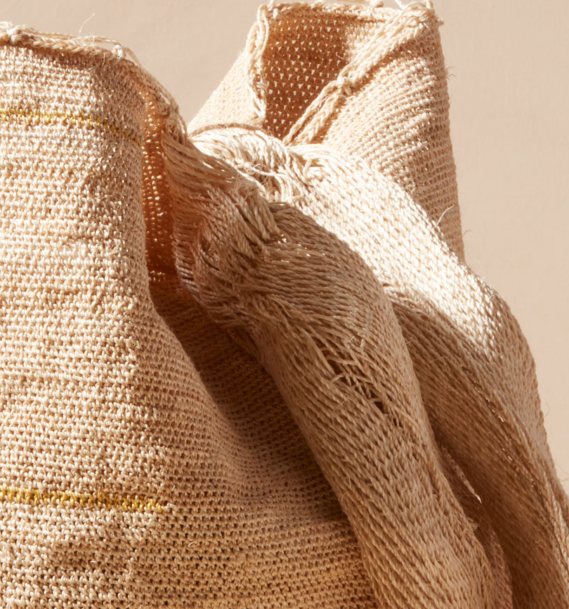 Close-up of beige woven straps of bag against a beige background