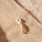 Detail view of clump of woven thread near the top of the beige woven bag
