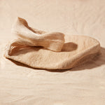 Flat view of beige woven bag on a sand surface