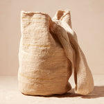 Beige woven bag with a strap on a beige background