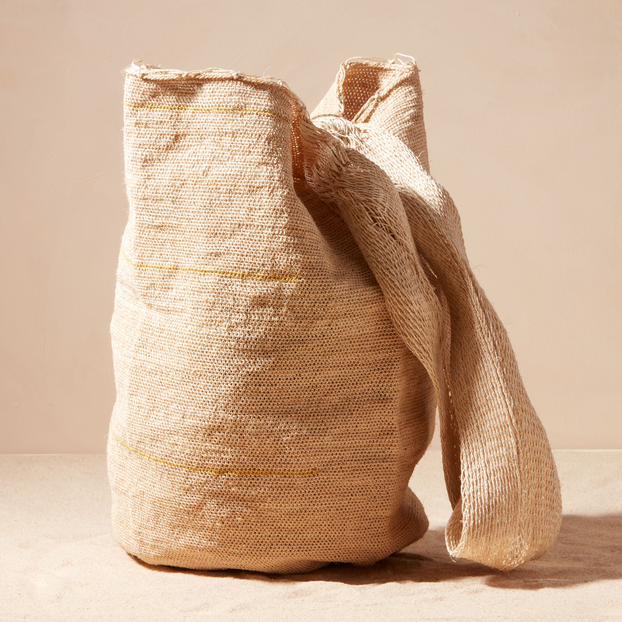 Beige woven bag with a strap on a beige background