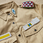 Detailed view of the colorful hand beaded patches on the khaki safari shirt with pockets