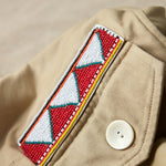 Close up view of colorful geometric hand beaded patch on the khaki ranger safari jacket