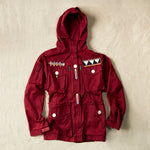 Red ranger hooded safari jacket with colorful hand beaded patches on a sand background