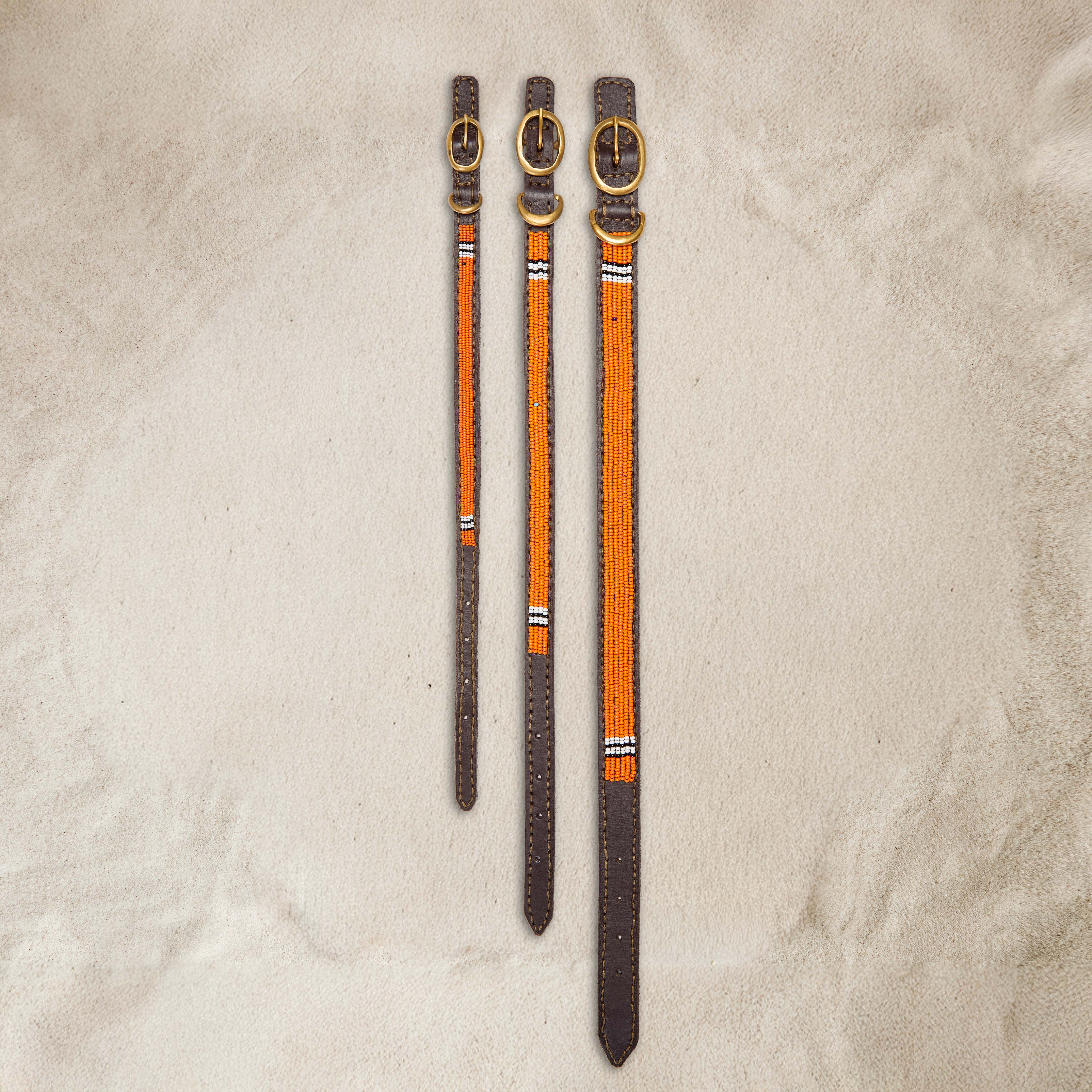 Small, Medium, and Large sizes of the leather dog collar with orange beads with accents of black and white beads and a brass buckle