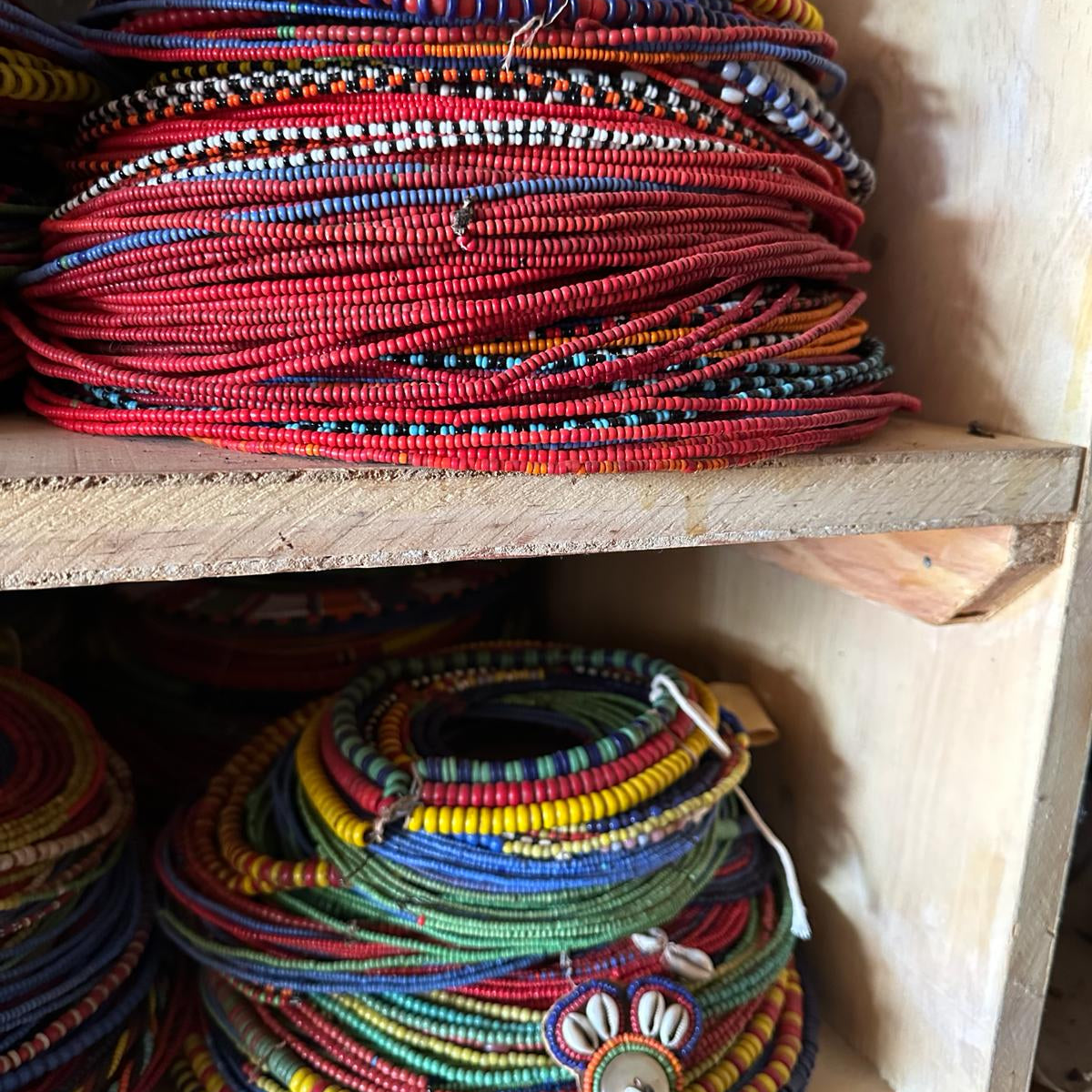 Colorful bangles and necklaces stacked on a wooden shelf
