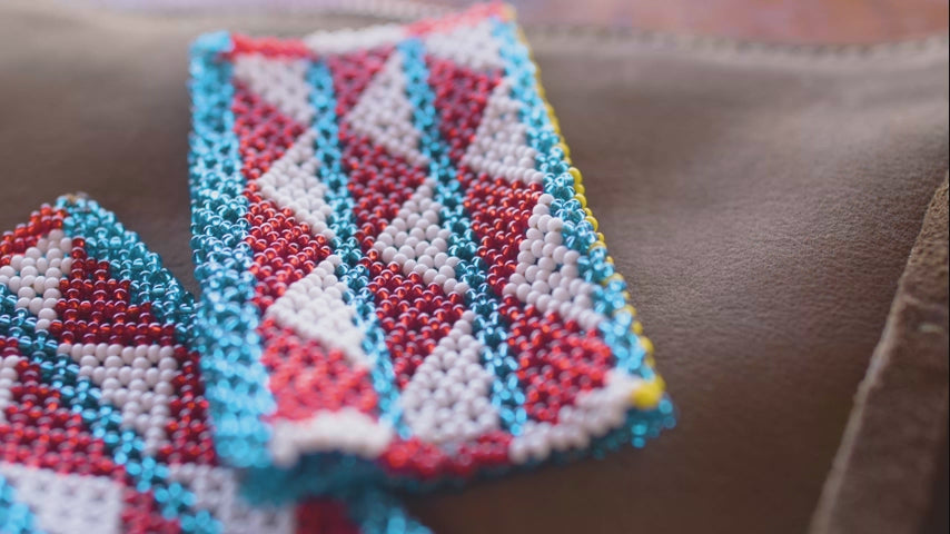 Video of details of colorful beaded necklaces, patches and products being created.